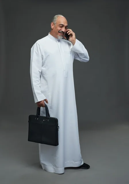 رجل أعمال سعودي بالثوب يتحدث بالهاتف مع حقيبة