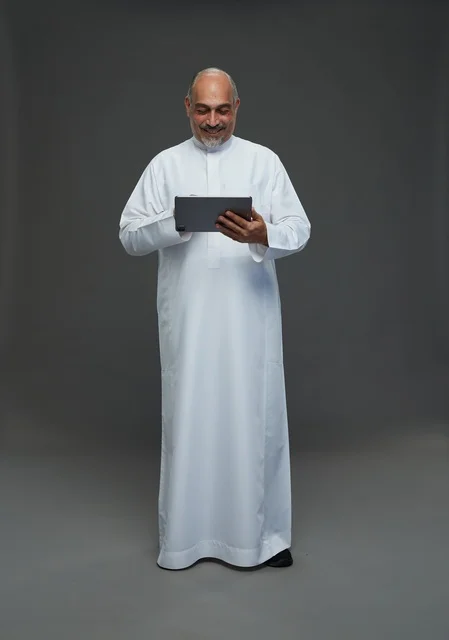 Elderly Saudi Man Using Tablet on Grey Background