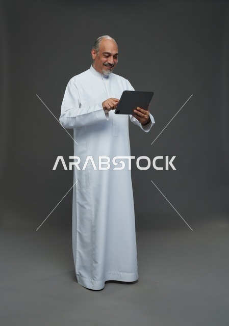 رجل سعودي مسن يستخدم جهازاً لوحياً في الاستوديو