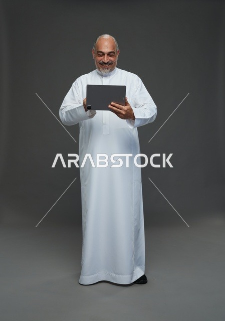 Senior Saudi Man Using Tablet on Gray Background