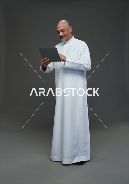 Senior Saudi Man Using Digital Tablet Against Grey Background
