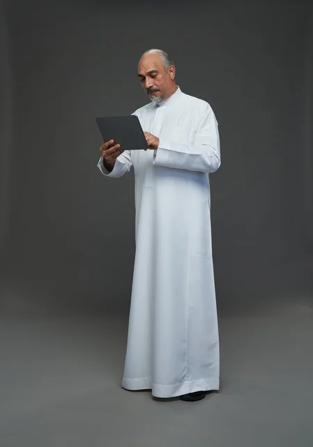 Senior Saudi Man Using Tablet on Grey Background