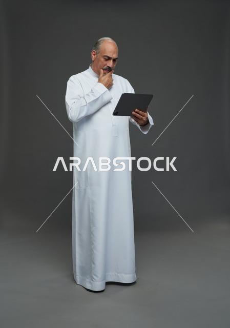 Saudi Elderly Man Using Tablet on Gray Background