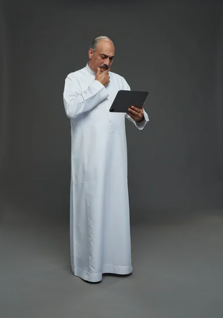 Saudi Elderly Man Using Tablet on Gray Background