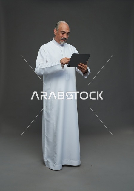 رجل سعودي مسن يستخدم جهاز لوحي في الاستوديو