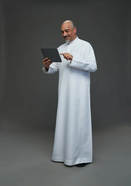 رجل سعودي مسن يستخدم جهاز لوحي في الاستوديو