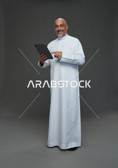 Smiling Elderly Saudi Man Using Tablet in Studio