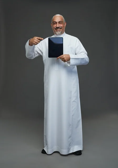 رجل سعودي مسن يشير إلى جهاز لوحي في الاستوديو