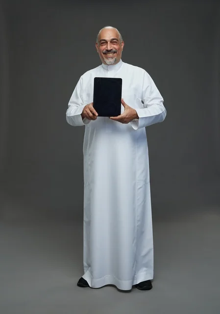 رجل سعودي مسن يحمل جهاز لوحي في الاستوديو