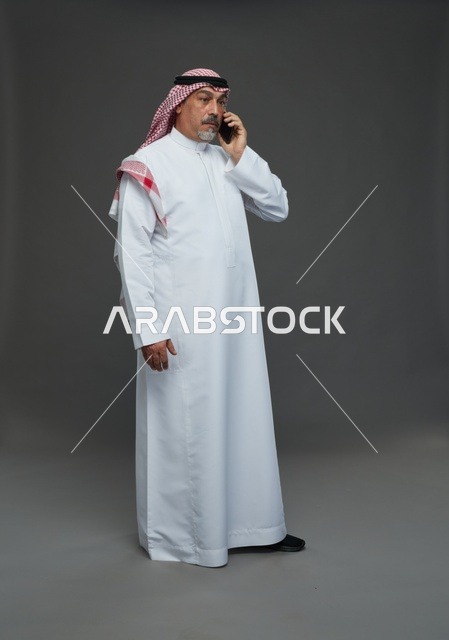 رجل سعودي مسن يتحدث بالهاتف الذكي في الاستوديو