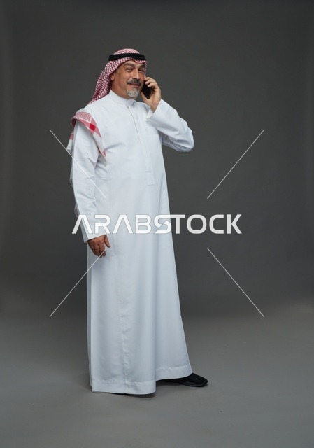 رجل سعودي مسن يبتسم أثناء التحدث في الهاتف