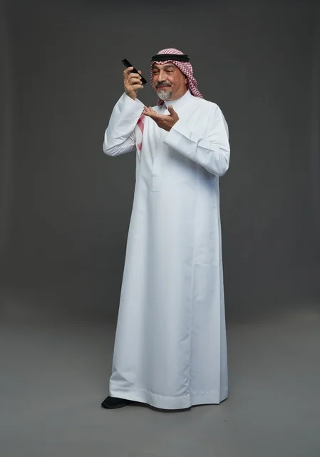 رجل سعودي مسن يبتسم يتحدث بالجوال