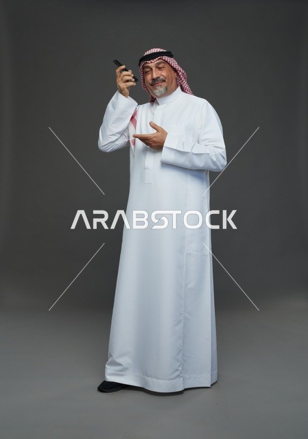 رجل سعودي مسن يتحدث بالهاتف المحمول في الاستوديو