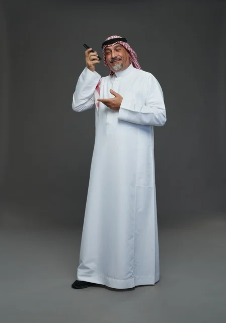رجل سعودي مسن يتحدث بالهاتف المحمول في الاستوديو