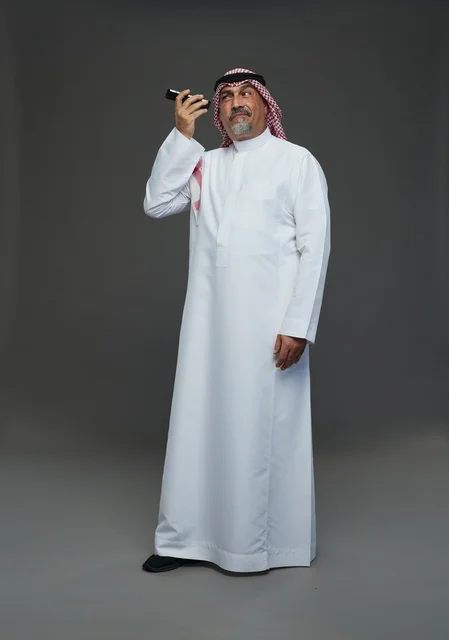 Elderly Saudi Man Using Smartphone on Gray Background