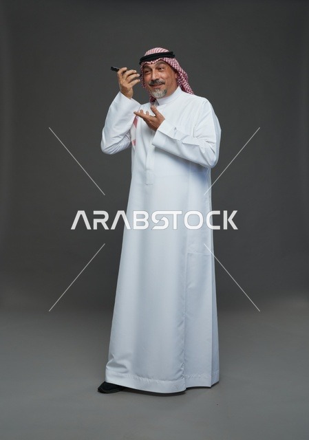 رجل سعودي مسن يبتسم مع هاتف ذكي في الاستوديو