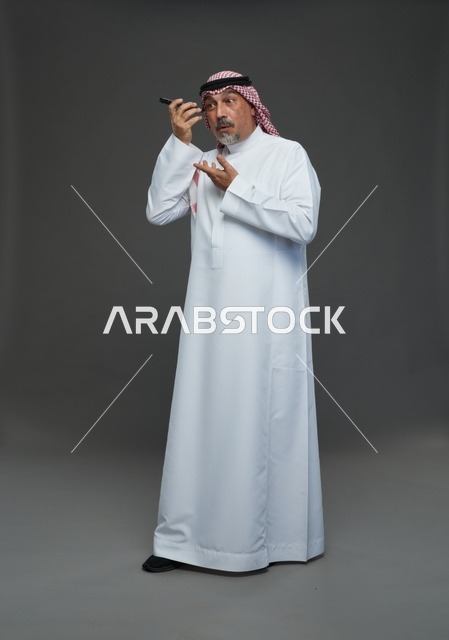 رجل سعودي مسن يستمع لرسالة صوتية بالهاتف