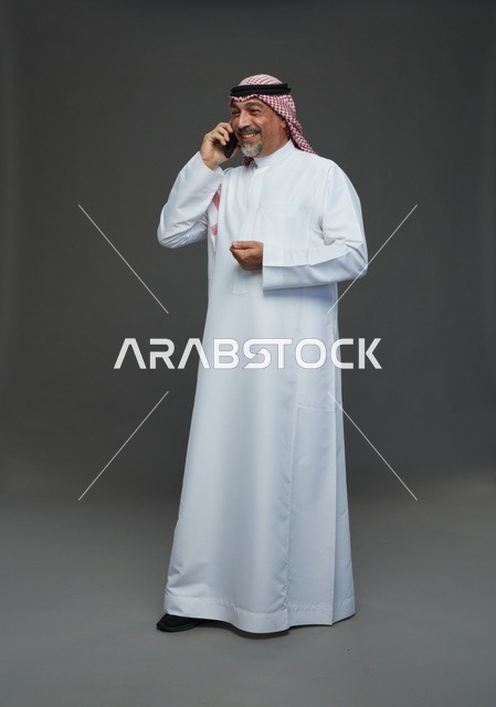 رجل سعودي مسن يبتسم أثناء التحدث في الهاتف