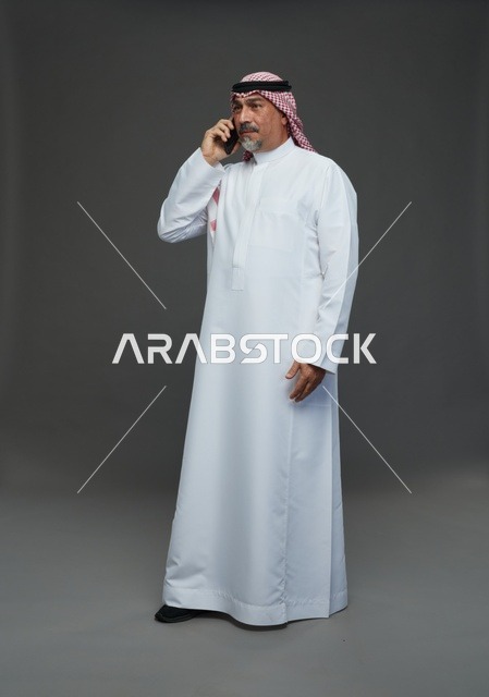 رجل سعودي مسن بالزي التقليدي يتحدث في الهاتف