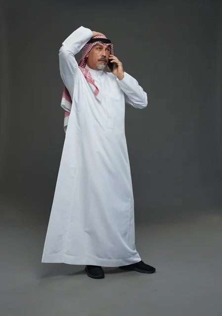 Saudi Man in Traditional Thobe Talking on Phone