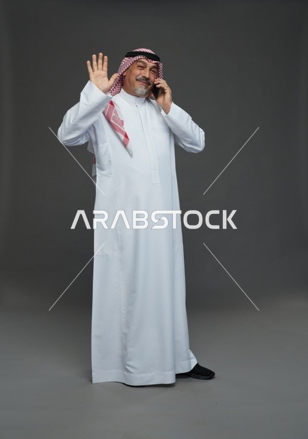 رجل سعودي مسن يتحدث بالهاتف الذكي ويلوح بيده