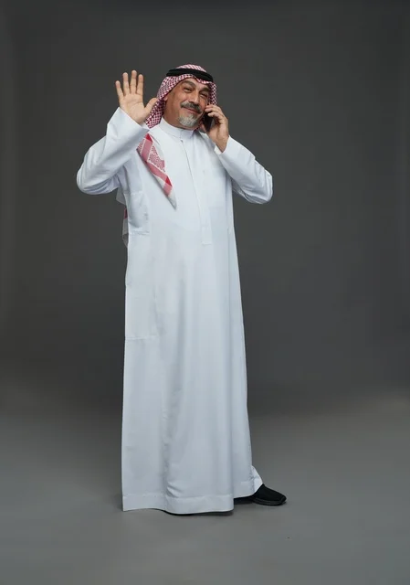 رجل سعودي مسن يتحدث بالهاتف الذكي ويلوح بيده
