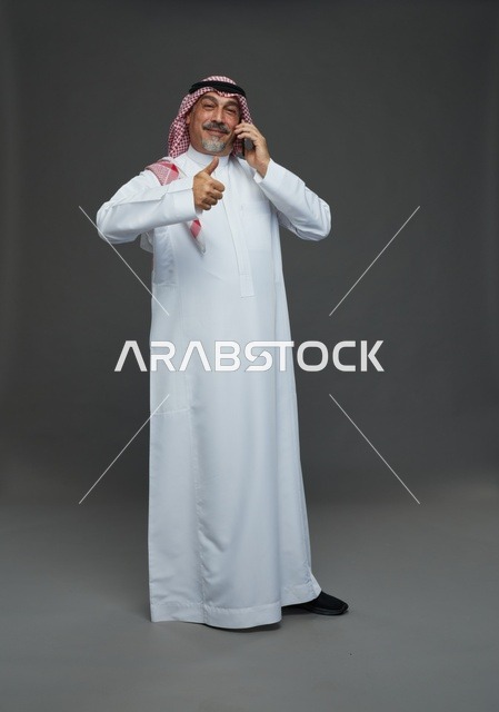 رجل سعودي مسن يتحدث بالهاتف مع علامة الإعجاب