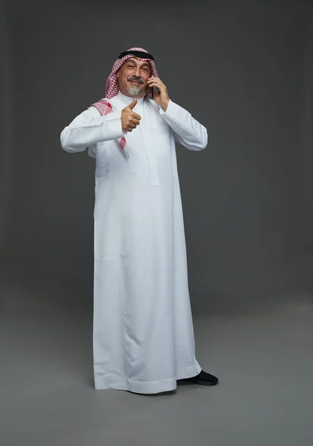 رجل سعودي مسن يتحدث بالهاتف مع علامة الإعجاب
