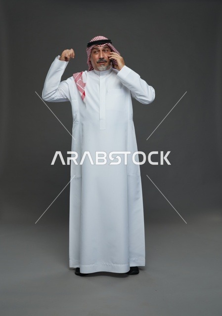 رجل سعودي مسن يحتفل بالنجاح أثناء التحدث في الهاتف المحمول