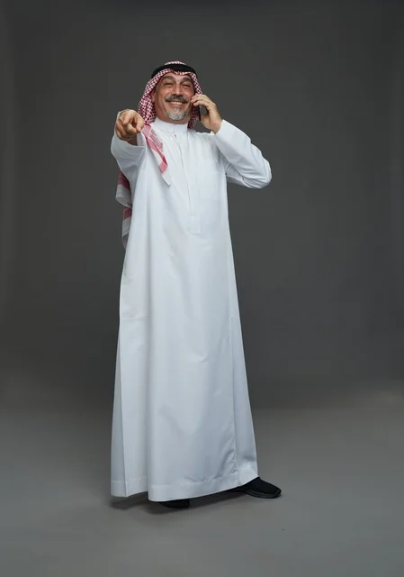 رجل سعودي مسن يبتسم أثناء التحدث في الهاتف