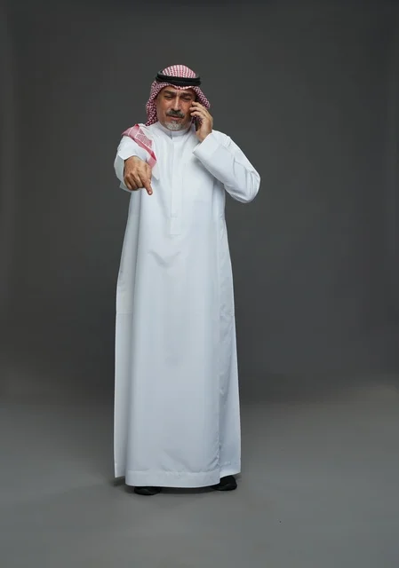 رجل سعودي مسن يتحدث بالهاتف ويشير للأمام