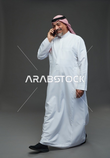 رجل سعودي مسن يمشي ويتحدث بالهاتف في الاستوديو