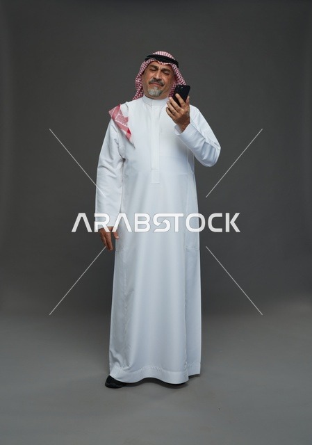 رجل سعودي مسن يبتسم في الهاتف في استوديو