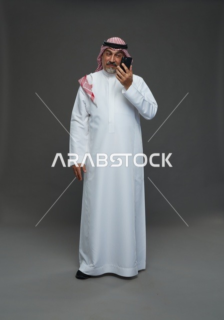 رجل سعودي مسن يبتسم أثناء التحدث بالهاتف في الاستوديو