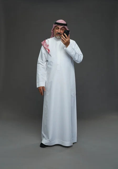 رجل سعودي مسن يبتسم أثناء التحدث بالهاتف في الاستوديو