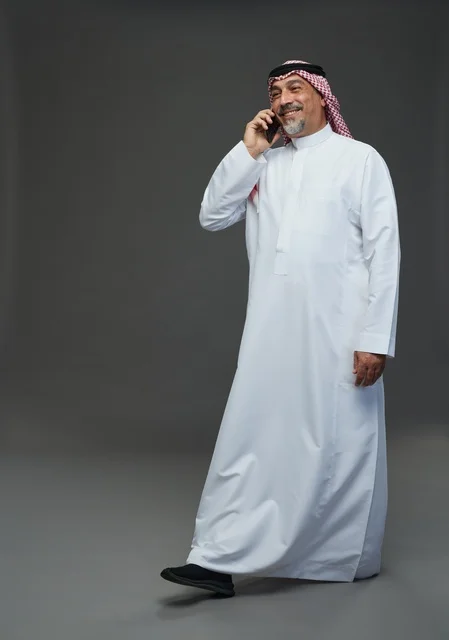 Saudi Senior Man Talking on Phone on Grey Background