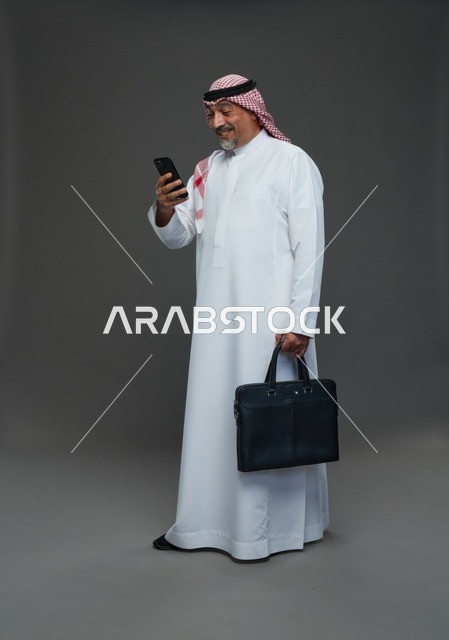 رجل أعمال سعودي مسن مع هاتف وحقيبة