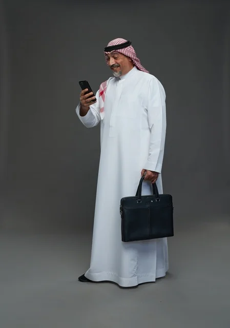 رجل أعمال سعودي مسن مع هاتف وحقيبة