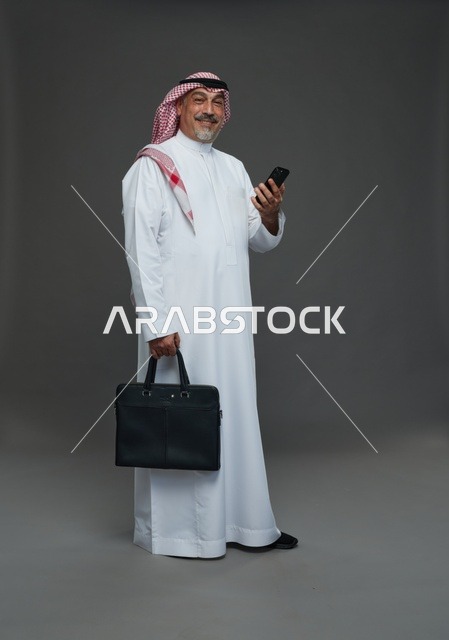 رجل أعمال سعودي يحمل حقيبة وهاتف محمول