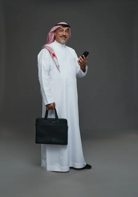 رجل أعمال سعودي يحمل حقيبة وهاتف محمول