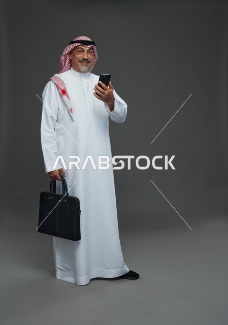 رجل أعمال سعودي مع هاتف وحقيبة في الاستوديو