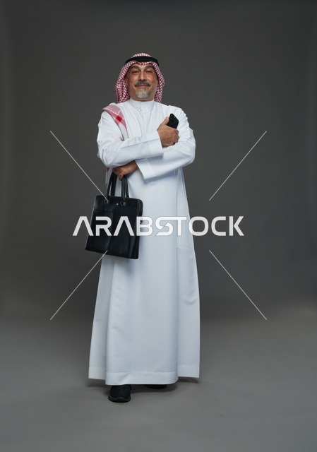 رجل أعمال سعودي يحمل حقيبة عمل وهاتف ذكي