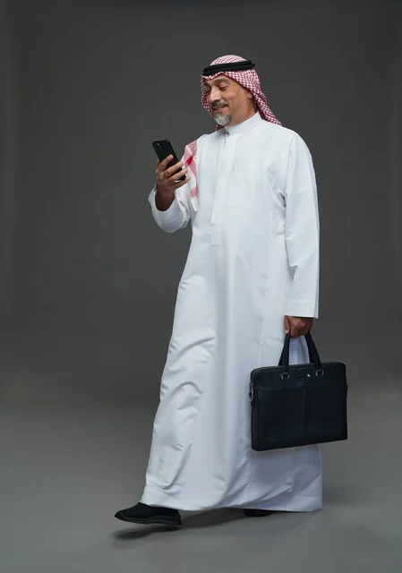 رجل أعمال سعودي مع هاتف محمول وحقيبة عمل
