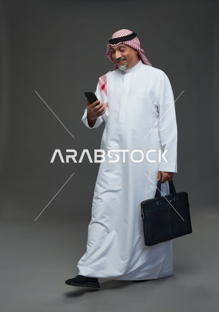 رجل أعمال سعودي يحمل حقيبة وهاتف ذكي