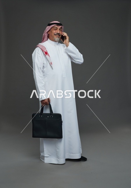 رجل أعمال سعودي يتحدث بالهاتف ويحمل حقيبة