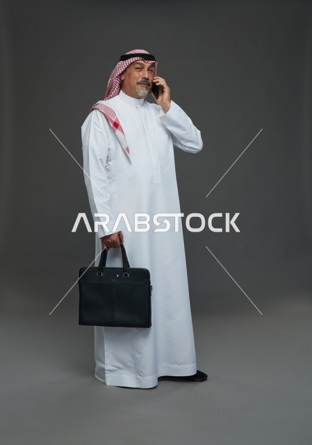 رجل أعمال سعودي يحمل حقيبة ويتحدث بالهاتف في استوديو