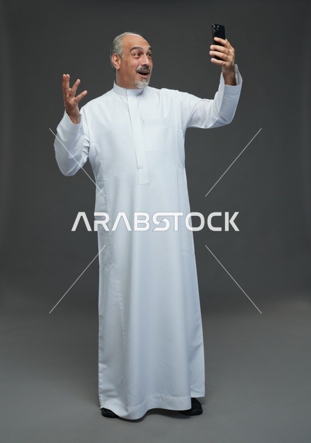Elderly Saudi Man Using Smartphone on Grey Background