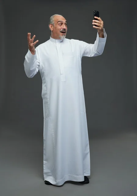 Elderly Saudi Man Using Smartphone on Grey Background
