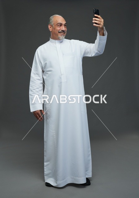 Senior Saudi Man in White Thobe Taking Smartphone Selfie