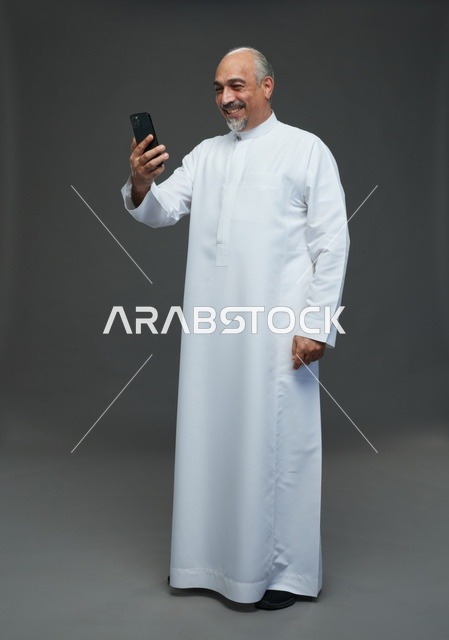 Senior Saudi Man Using Smartphone in Studio